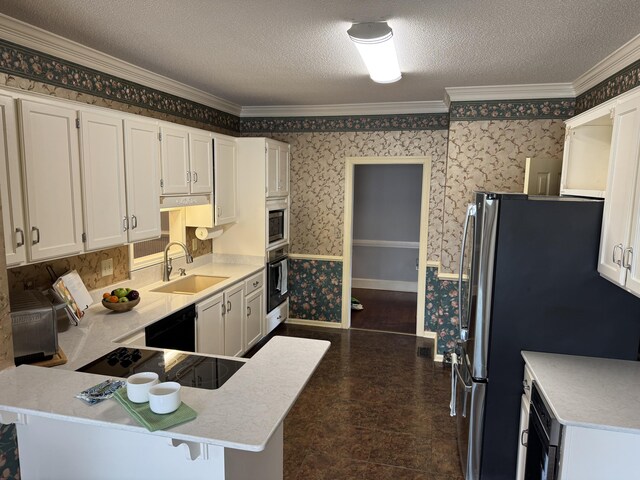 kitchen featuring a sink, light countertops, baseboards, wallpapered walls, and black appliances
