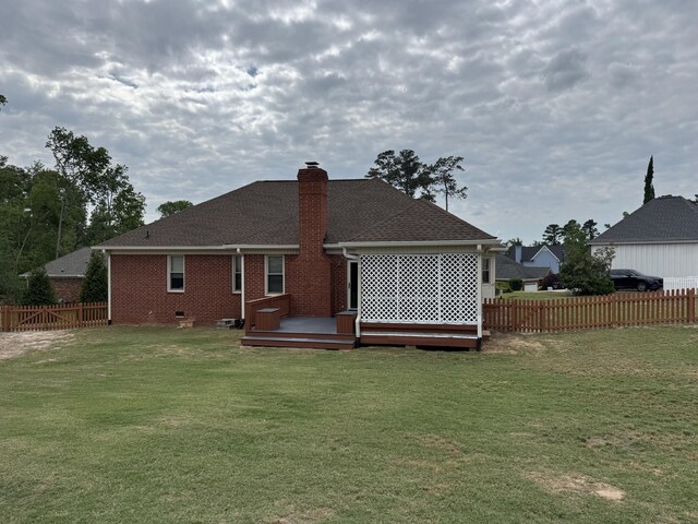 rear view of property with fence, a yard, and a deck