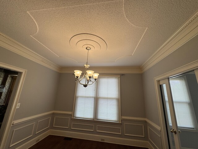 spare room with ornamental molding, a textured ceiling, a wainscoted wall, and a notable chandelier