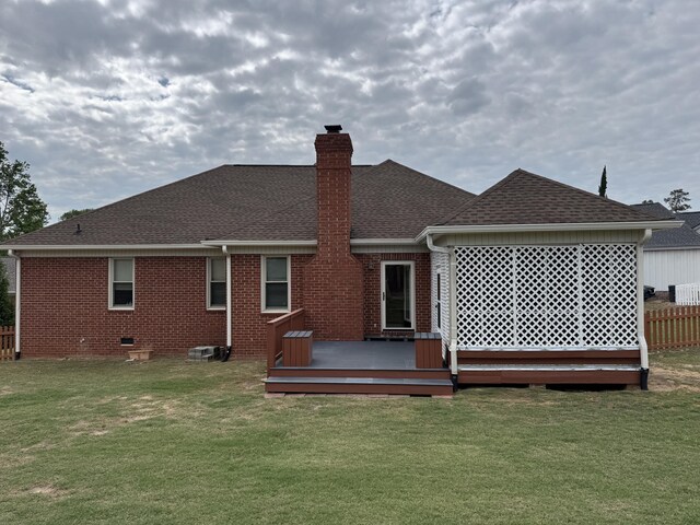 rear view of property with brick siding, a shingled roof, a lawn, and a chimney