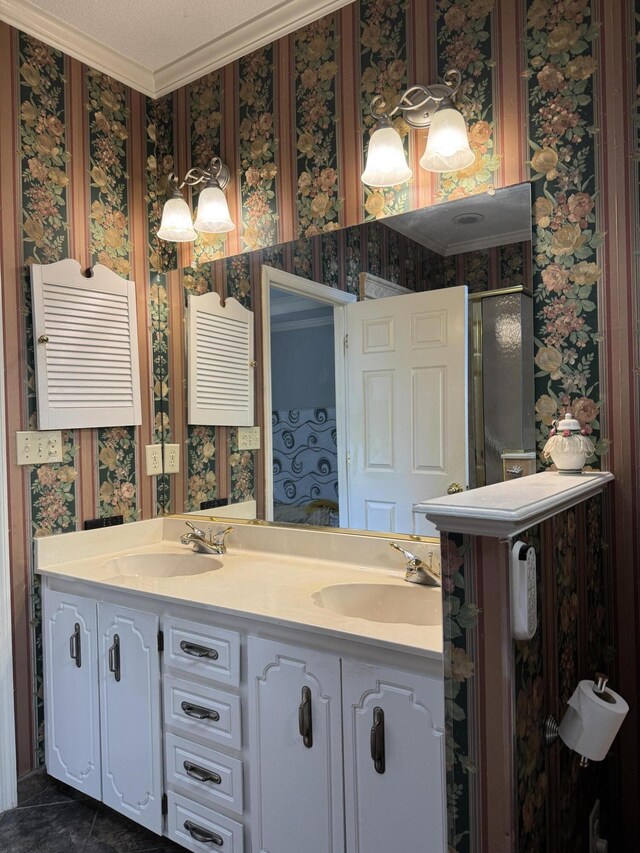 full bathroom with double vanity, wallpapered walls, ornamental molding, and a sink