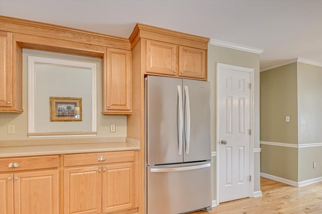 kitchen featuring light wood finished floors, baseboards, freestanding refrigerator, light countertops, and crown molding