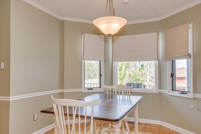 dining space featuring baseboards, wood finished floors, visible vents, and crown molding