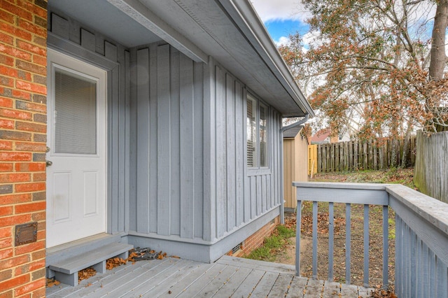 exterior space featuring fence, a deck, board and batten siding, and brick siding