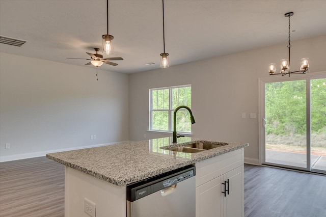 kitchen featuring open floor plan, stainless steel dishwasher, a sink, and light wood-style flooring