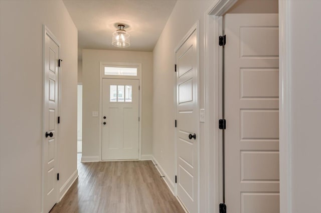 doorway to outside featuring light wood finished floors and baseboards
