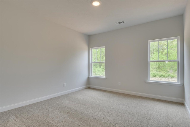 unfurnished room featuring visible vents, baseboards, and light colored carpet