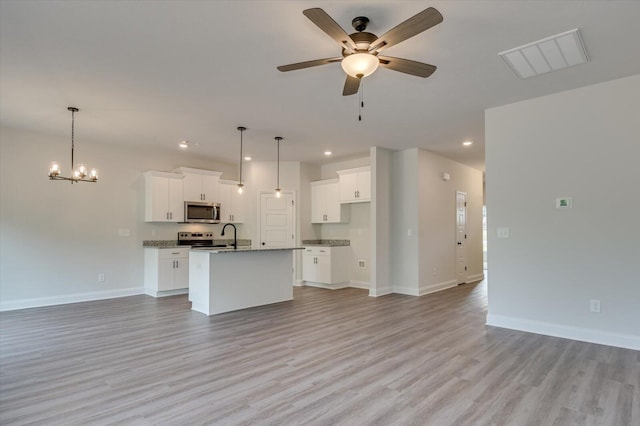 kitchen featuring visible vents, appliances with stainless steel finishes, open floor plan, an island with sink, and baseboards
