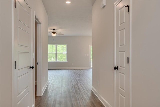 hallway featuring baseboards, dark wood-type flooring, and recessed lighting