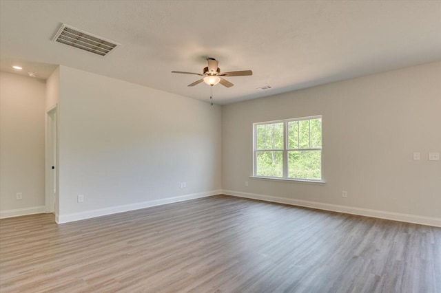 spare room featuring ceiling fan, wood finished floors, visible vents, and baseboards