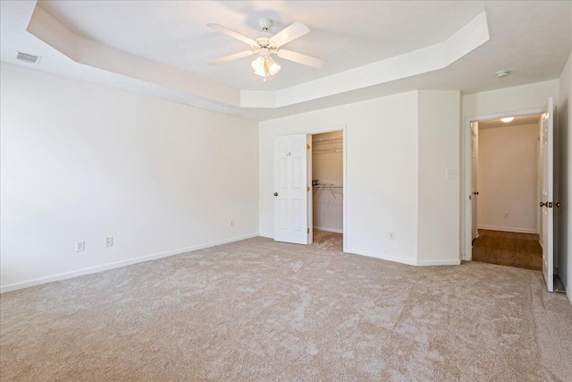 2071 Lake Forest Dr, Grovetown, GA 30813 - unfurnished bedroom with carpet floors, a tray ceiling, a walk in closet, and a ceiling fan