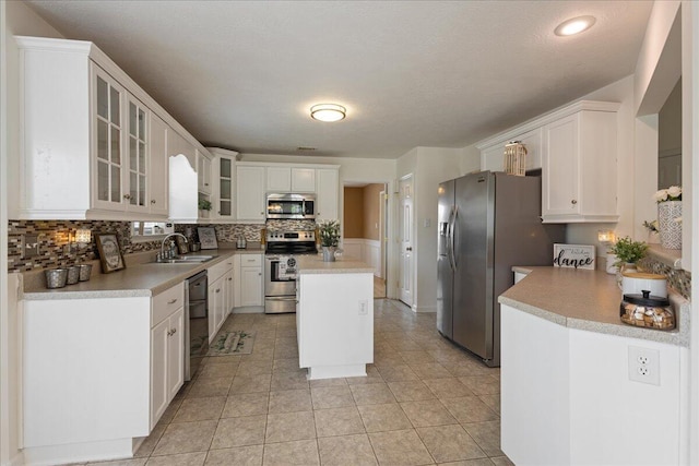 2071 Lake Forest Dr, Grovetown, GA 30813 - kitchen with appliances with stainless steel finishes, tasteful backsplash, white cabinetry, glass insert cabinets, and light countertops