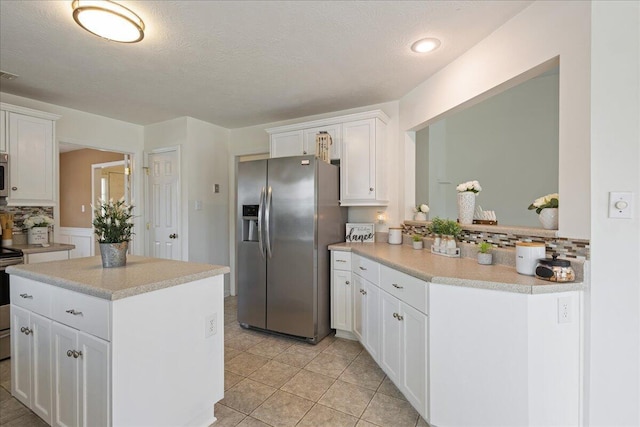2071 Lake Forest Dr, Grovetown, GA 30813 - kitchen with stainless steel appliances, light countertops, white cabinets, a kitchen island, and a textured ceiling