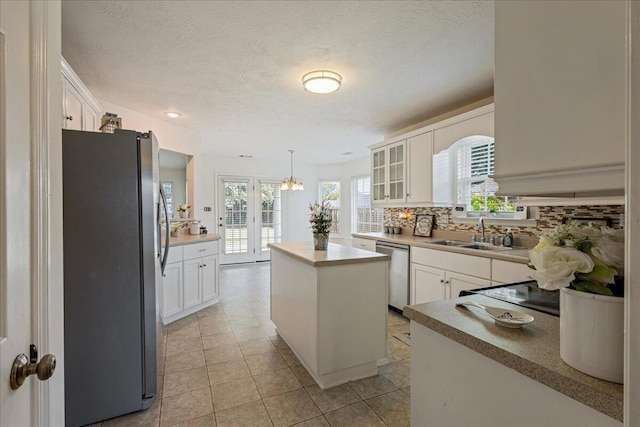 2071 Lake Forest Dr, Grovetown, GA 30813 - kitchen featuring appliances with stainless steel finishes, a kitchen island, decorative backsplash, white cabinetry, and a textured ceiling