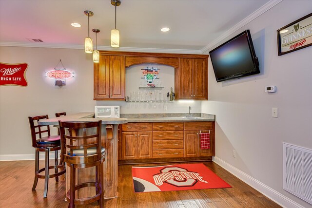 203 Jacque Cir, Mccormick, SC 29835 - indoor wet bar featuring crown molding, baseboards, dark wood finished floors, hanging light fixtures, and white microwave