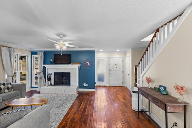 living room featuring hardwood / wood-style flooring, stairway, a fireplace, crown molding, and baseboards