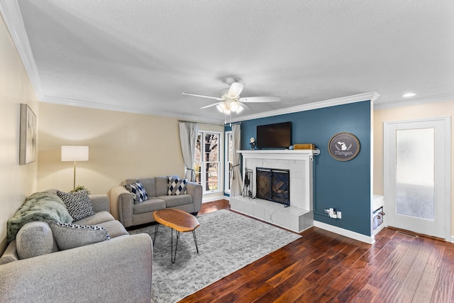 living area featuring a tile fireplace, crown molding, baseboards, and wood finished floors