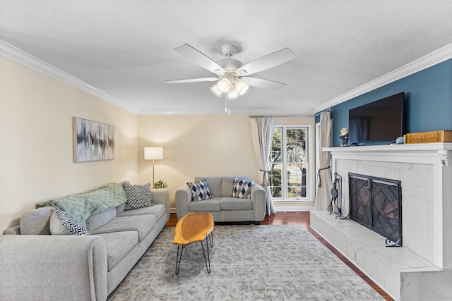 living room featuring a textured ceiling, wood finished floors, crown molding, and a tiled fireplace