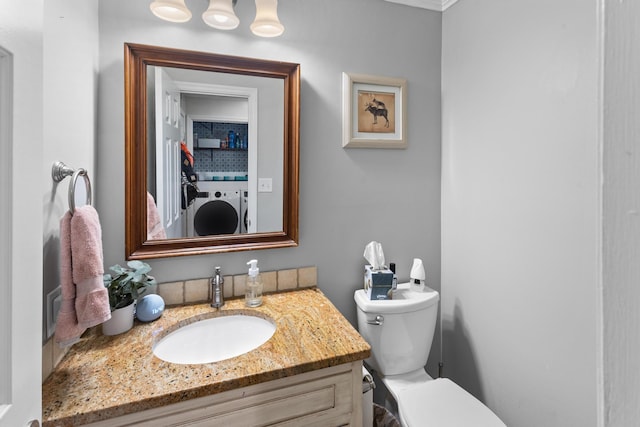 bathroom with washer and clothes dryer, toilet, and vanity