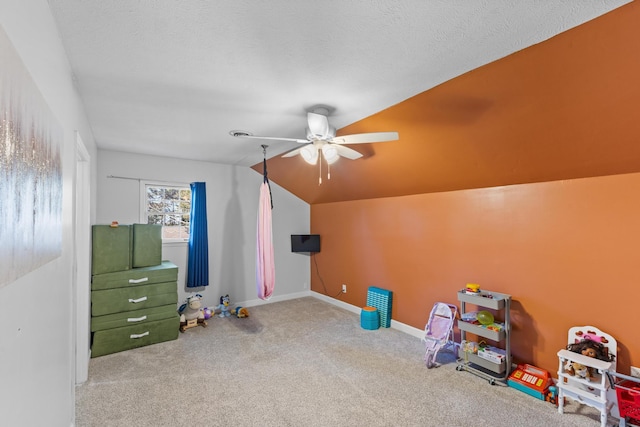 rec room with a textured ceiling, carpet flooring, baseboards, ceiling fan, and vaulted ceiling