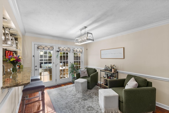 sitting room with dark wood finished floors, french doors, a textured ceiling, and ornamental molding