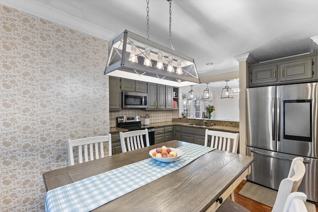 dining room with wallpapered walls, crown molding, and wood finished floors