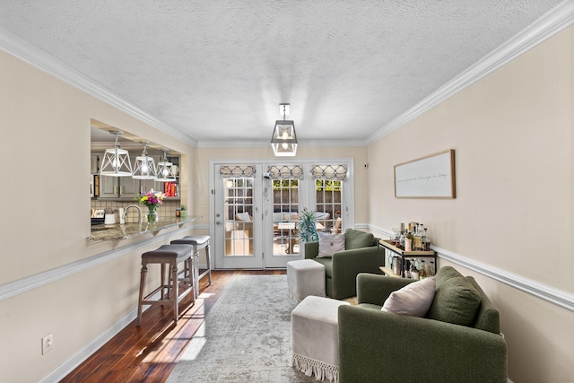 living area featuring crown molding, baseboards, wood-type flooring, and a textured ceiling