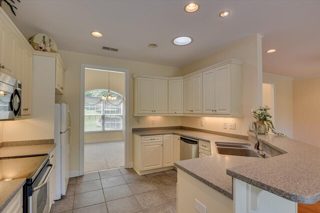 kitchen featuring kitchen peninsula, sink, appliances with stainless steel finishes, white cabinetry, and a chandelier