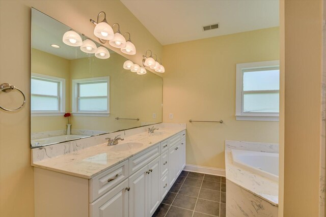 bathroom featuring tile patterned flooring, vanity, tiled tub, and a wealth of natural light