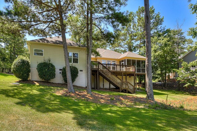 back of house featuring a sunroom, a wooden deck, and a lawn