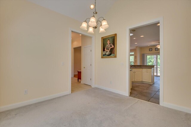 carpeted empty room with a notable chandelier