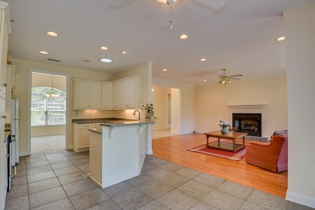 kitchen featuring white cabinets, ceiling fan with notable chandelier, kitchen peninsula, and light tile patterned floors