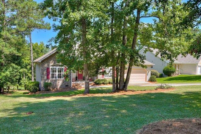 view of property hidden behind natural elements featuring a front yard and a garage