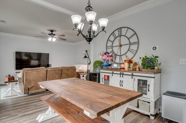 dining room featuring hardwood / wood-style flooring, ceiling fan with notable chandelier, and ornamental molding