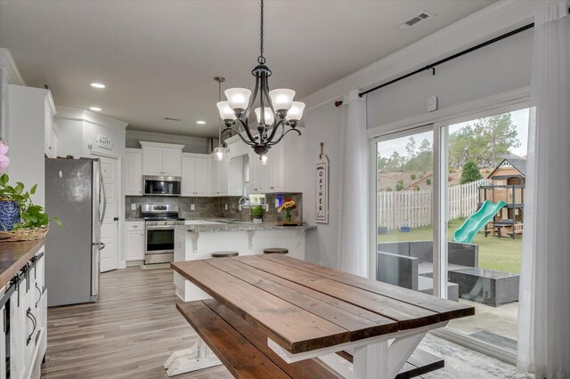 dining space featuring light hardwood / wood-style flooring, an inviting chandelier, crown molding, and sink