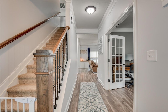 staircase featuring hardwood / wood-style floors and crown molding