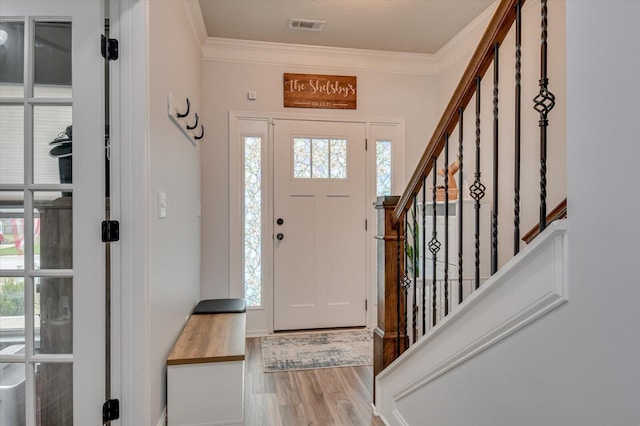 entryway with a healthy amount of sunlight, light hardwood / wood-style floors, and ornamental molding