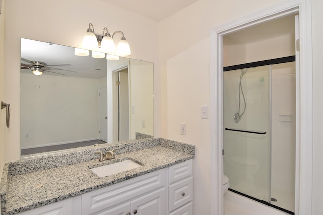 bathroom with ceiling fan, a shower with door, vanity, and toilet