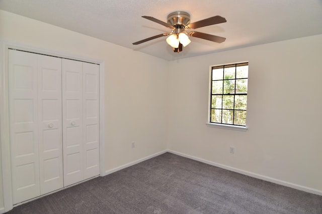 unfurnished bedroom with dark colored carpet, ceiling fan, and a closet