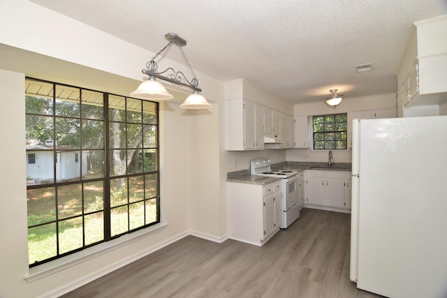 kitchen with light wood-type flooring, white appliances, sink, white cabinets, and hanging light fixtures