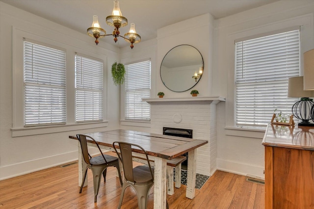 dining area featuring light wood-type flooring, visible vents, and a notable chandelier