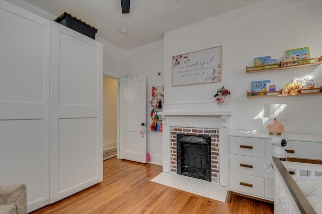 bedroom featuring light wood finished floors and a brick fireplace