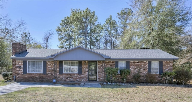 ranch-style home with a front lawn, a chimney, and brick siding