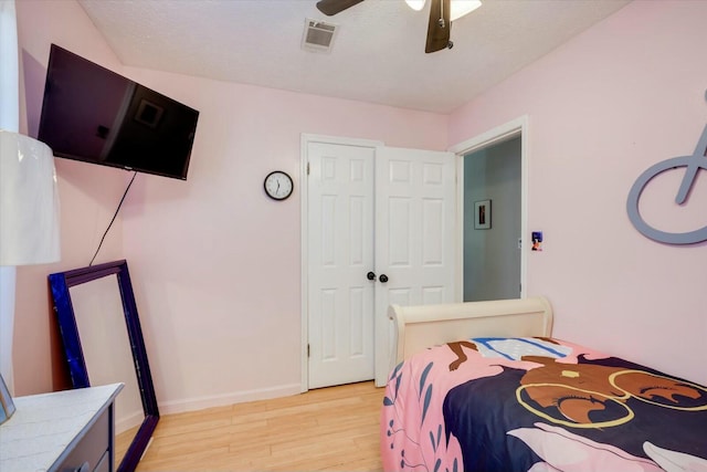 bedroom featuring light wood-type flooring, baseboards, visible vents, and a textured ceiling