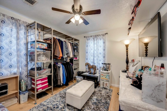 bedroom featuring a ceiling fan, visible vents, a textured ceiling, and wood finished floors