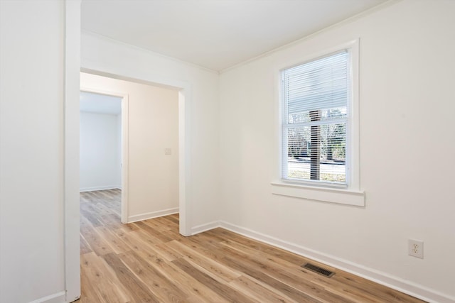 empty room with crown molding and light hardwood / wood-style flooring