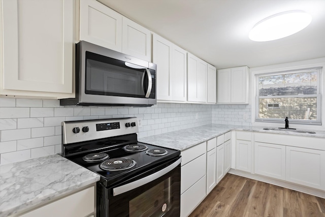 kitchen with white cabinetry, sink, electric range, and backsplash