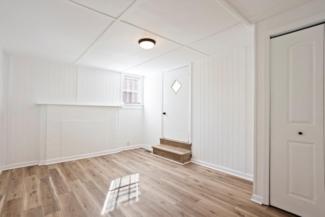 interior space with a fireplace, light hardwood / wood-style flooring, and a drop ceiling