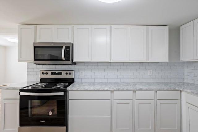 kitchen featuring white cabinetry, decorative backsplash, light stone countertops, and electric range oven