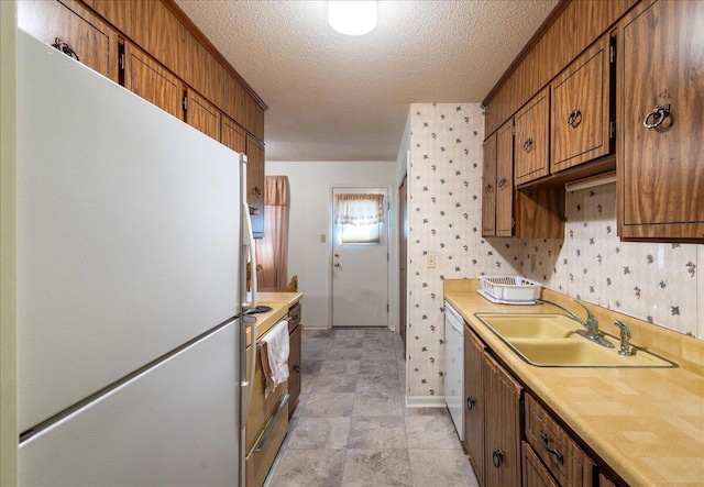 kitchen with sink, white appliances, and a textured ceiling